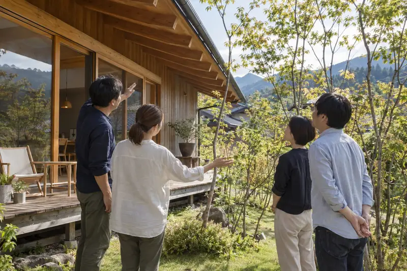 住んで5年の木の家の居間で、住まい手の家族が来訪者を案内している様子