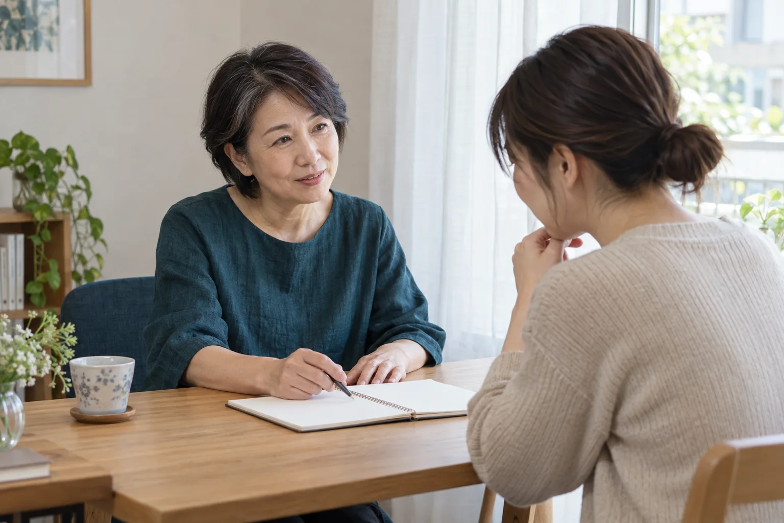 木の机を挟み、相談者の話を聞くカウンセラーのイメージ